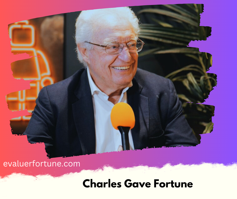 Un homme avec les cheveux blancs et portant une veste sombre parle dans un microphone orange. L'arrière-plan montre une plante et une enseigne lumineuse. Le texte "evaluerfortune.com" et "Charles Gave Fortune" est visible.