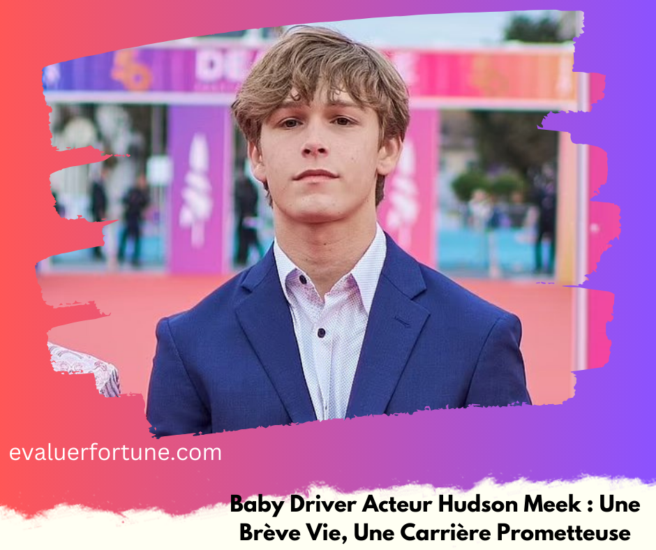 Un homme en costume bleu se tient devant un fond coloré avec des panneaux et des personnes floues en arrière-plan. Le texte en bas de l'image mentionne "Baby Driver Acteur Hudson Meek : Une Brève Vie, Une Carrière Prometteuse".